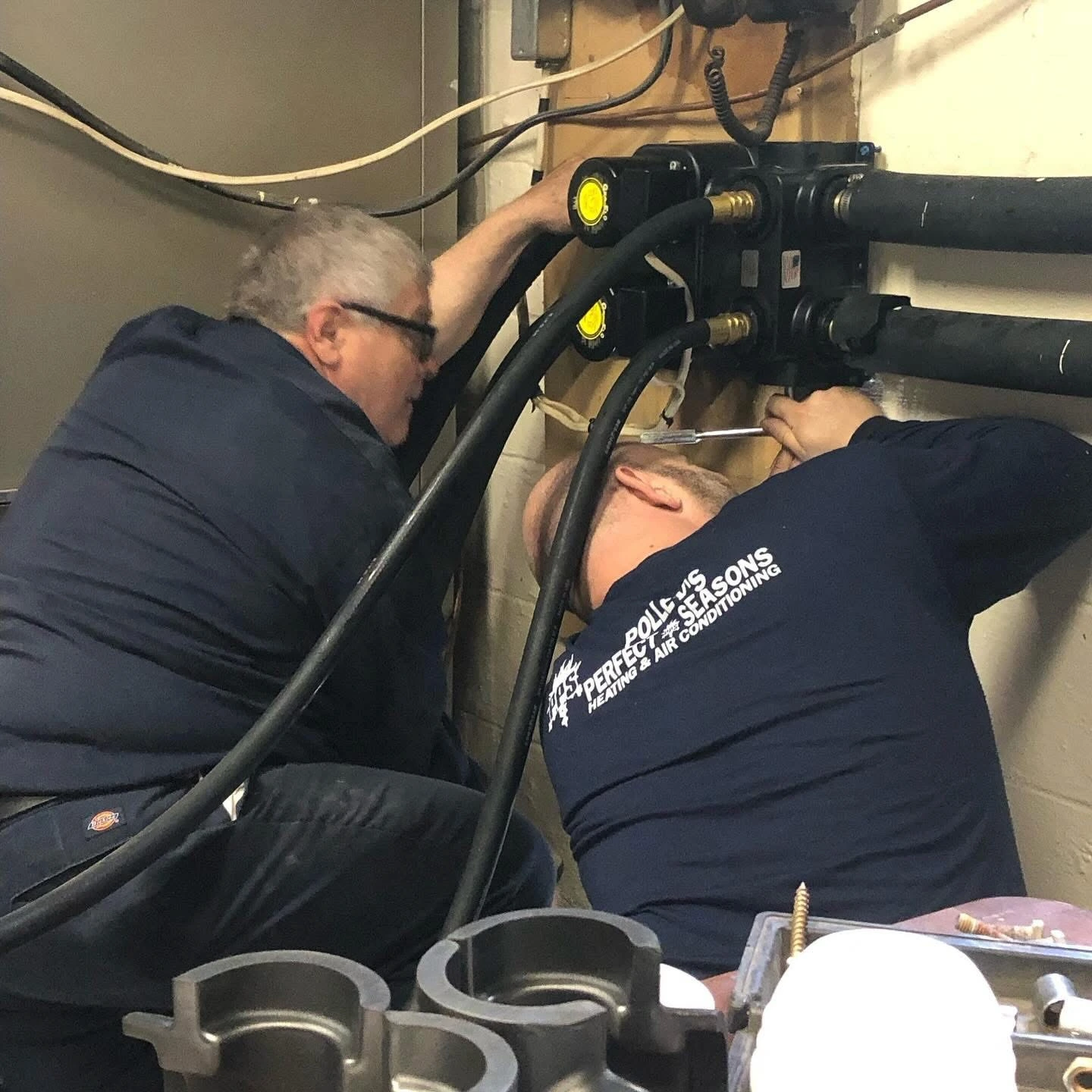 Two Polley's Perfect Seasons technicians installing a new geothermal flow center and circulator pumps in a Plainfield, IN basement